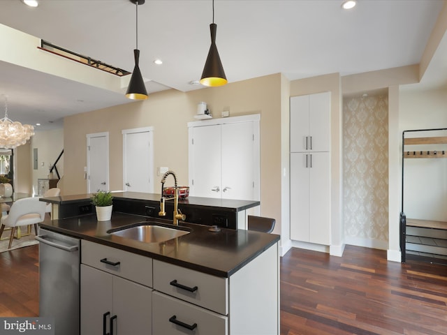 kitchen with dark hardwood / wood-style flooring, sink, a center island with sink, white cabinets, and hanging light fixtures