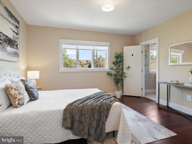 bedroom featuring dark hardwood / wood-style flooring and ensuite bath