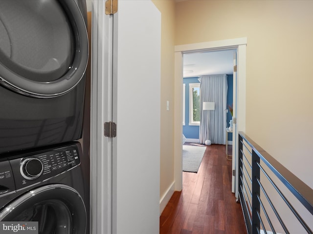 clothes washing area featuring stacked washer / dryer and dark wood-type flooring