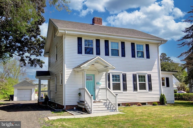 colonial house featuring an outbuilding, a front lawn, and a garage