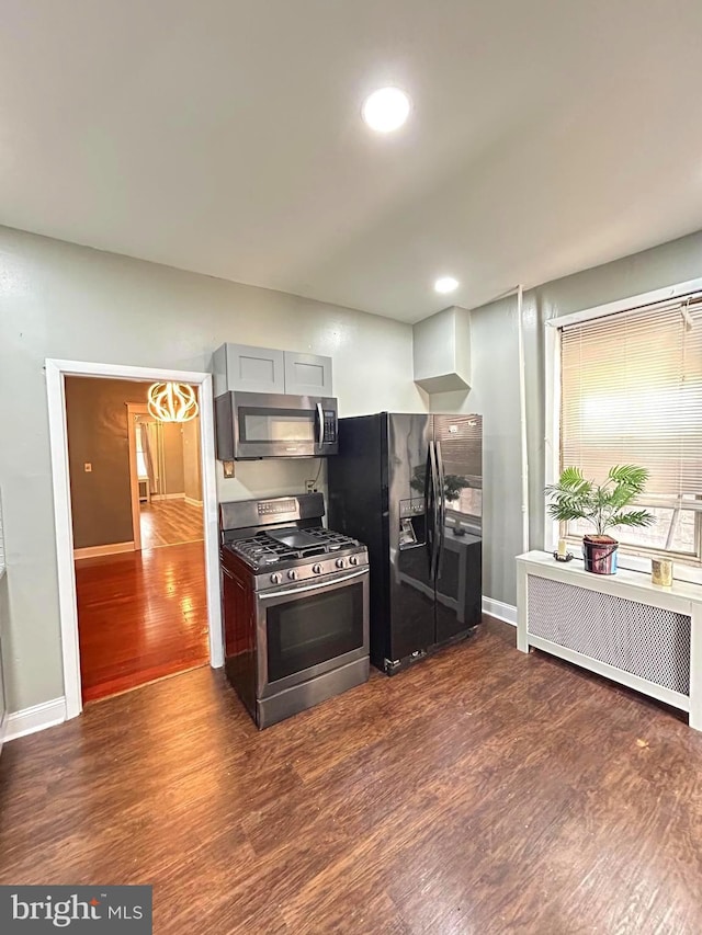 kitchen with appliances with stainless steel finishes, radiator heating unit, and dark wood-type flooring