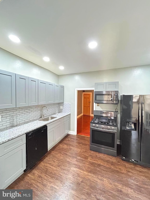 kitchen with light stone countertops, stainless steel appliances, dark wood-type flooring, and sink