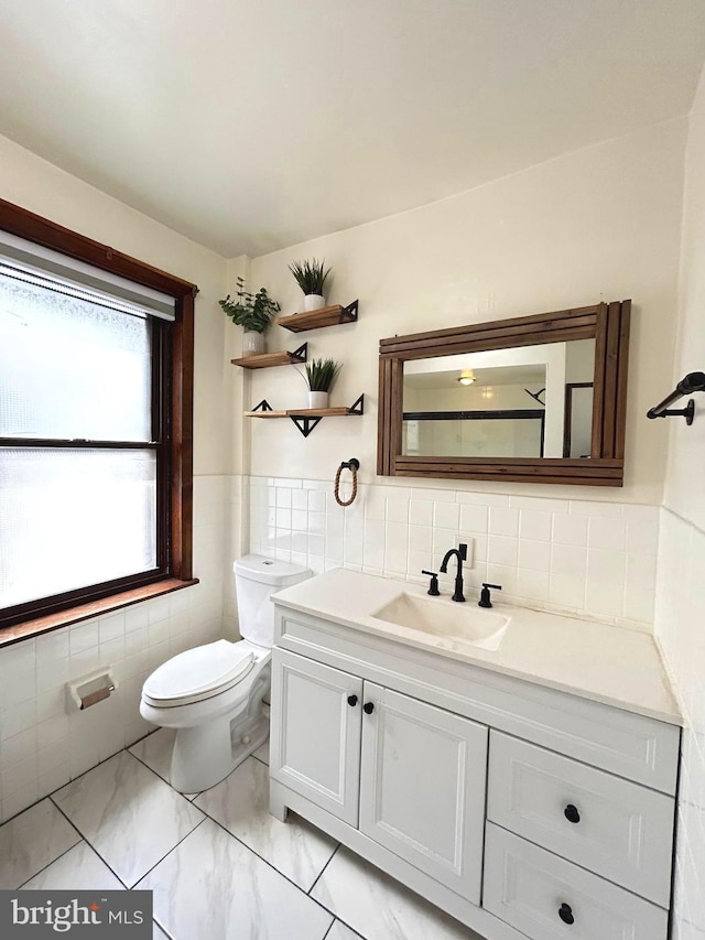 bathroom with vanity, toilet, and tile walls