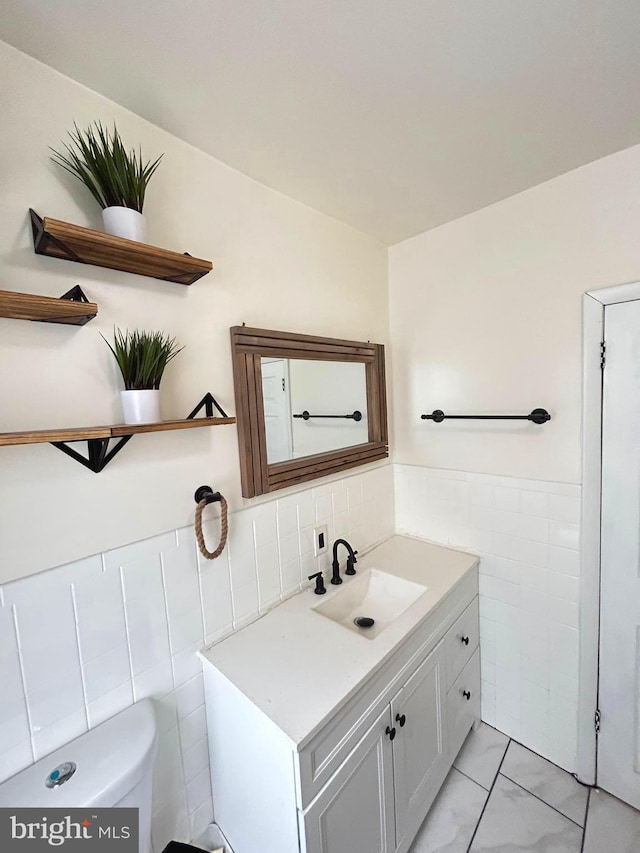 bathroom with vanity, toilet, and tile walls