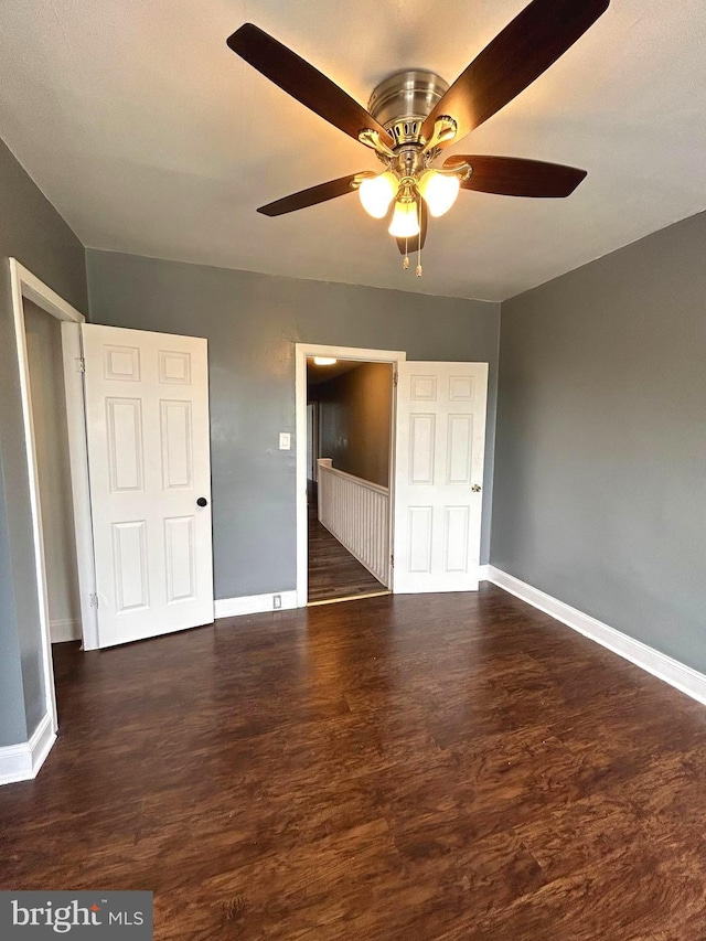 unfurnished bedroom with ceiling fan and dark wood-type flooring