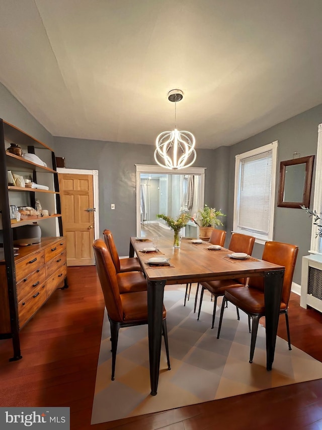 dining space featuring dark wood-type flooring, a chandelier, and radiator heating unit