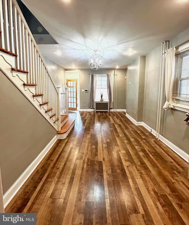 foyer entrance featuring radiator, wood-type flooring, and an inviting chandelier