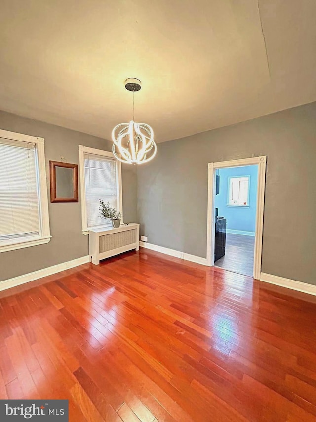 unfurnished dining area with radiator, a chandelier, and hardwood / wood-style flooring