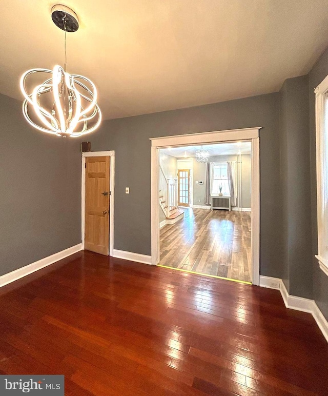 unfurnished dining area with hardwood / wood-style flooring, radiator, and an inviting chandelier