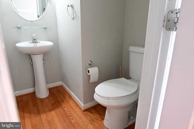 bathroom featuring wood-type flooring, toilet, and sink