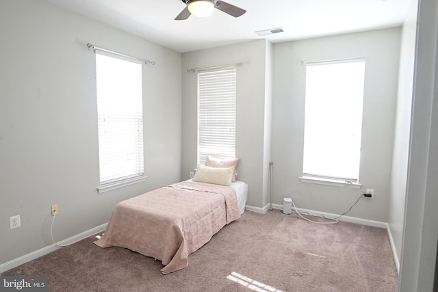 carpeted bedroom with multiple windows and ceiling fan