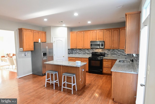 kitchen featuring sink, a center island, light stone counters, and appliances with stainless steel finishes