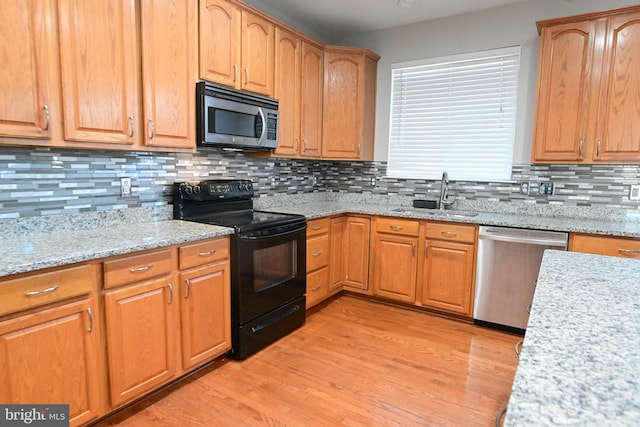 kitchen featuring appliances with stainless steel finishes, light wood-type flooring, backsplash, and sink