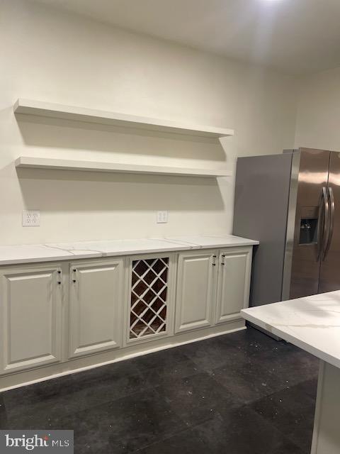 kitchen featuring light stone countertops and stainless steel fridge