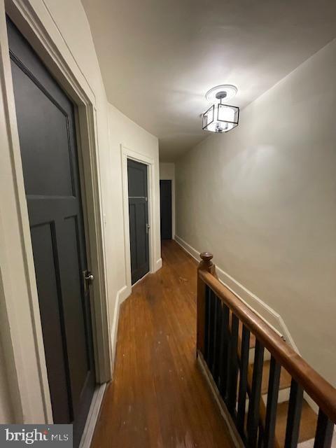 corridor featuring an upstairs landing, baseboards, and wood finished floors