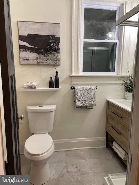 bathroom with toilet, vanity, and baseboards