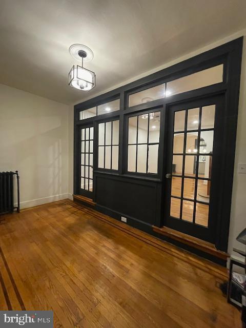 interior space with radiator, baseboards, and wood finished floors