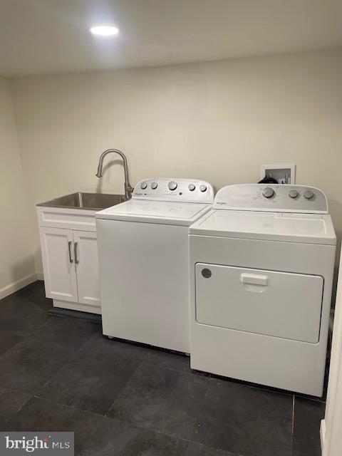 laundry area with a sink, cabinet space, baseboards, and washer and clothes dryer