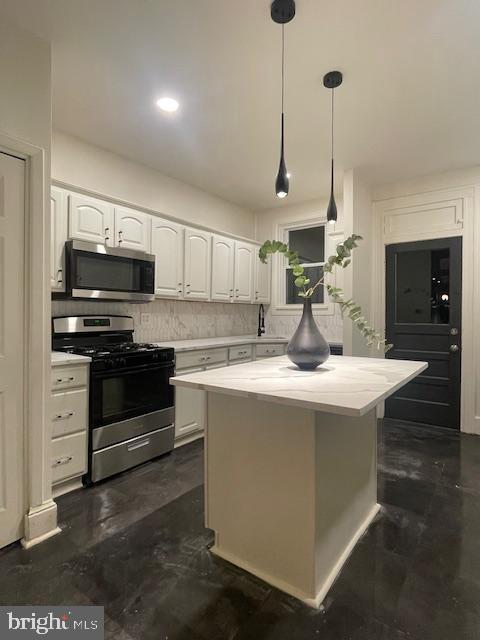 kitchen featuring stainless steel appliances, white cabinetry, and light countertops