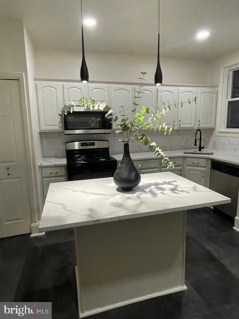 kitchen featuring backsplash, white cabinets, appliances with stainless steel finishes, and a sink