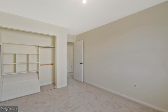 unfurnished bedroom featuring light carpet and a closet