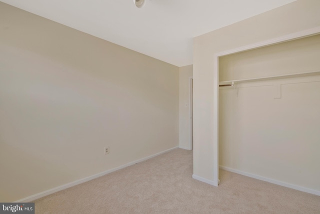 unfurnished bedroom with light carpet and a closet