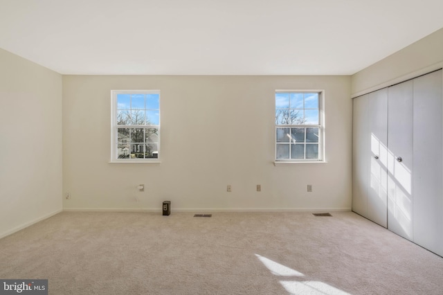 unfurnished bedroom featuring multiple windows and light carpet