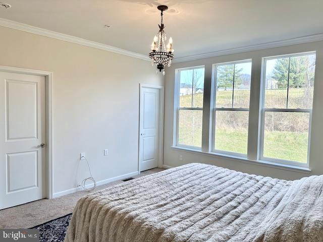 carpeted bedroom featuring crown molding and a chandelier