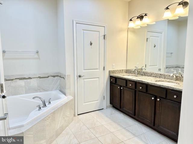 bathroom featuring tiled bath, tile patterned flooring, and vanity