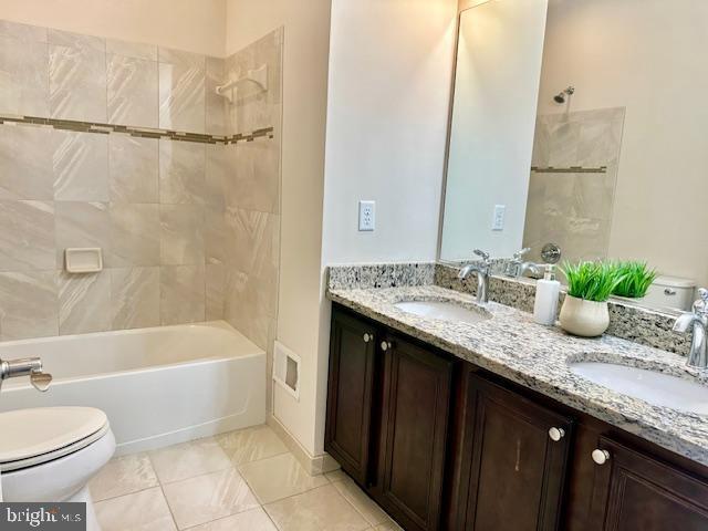 full bathroom with tile patterned floors, vanity, tiled shower / bath combo, and toilet