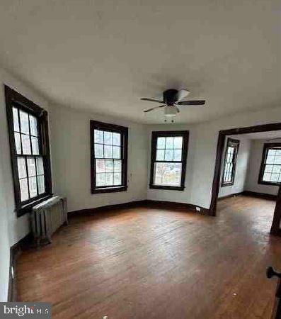 unfurnished living room featuring radiator heating unit and ceiling fan