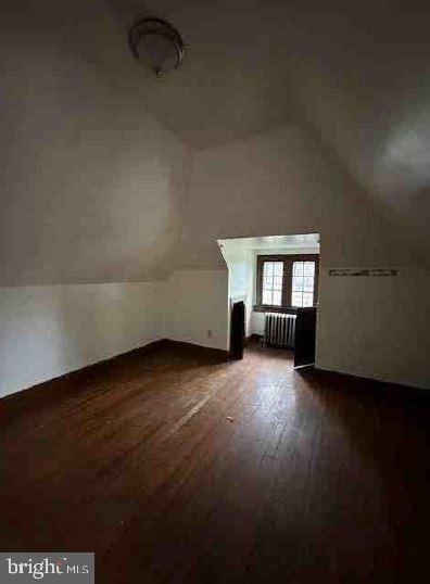 additional living space with dark hardwood / wood-style flooring, radiator, and lofted ceiling