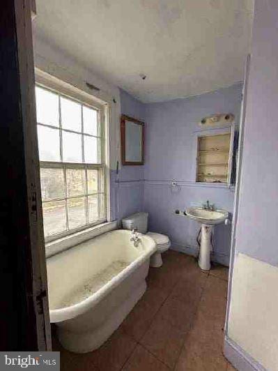 bathroom featuring tile patterned floors, a bathtub, and toilet