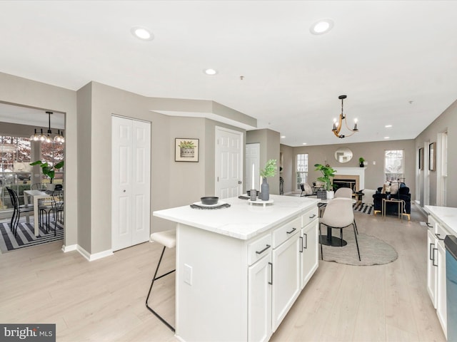 kitchen featuring a kitchen breakfast bar, pendant lighting, white cabinets, a center island, and a chandelier