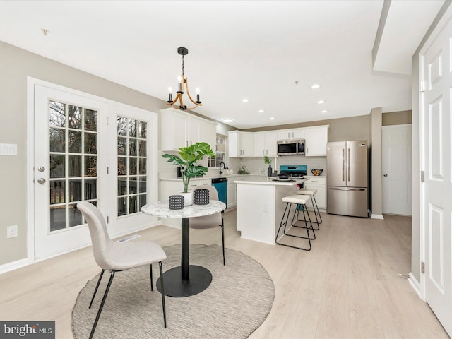 dining room featuring sink, light hardwood / wood-style flooring, and an inviting chandelier