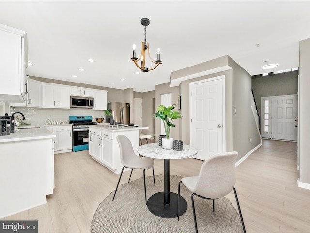 dining area with light hardwood / wood-style flooring, sink, and a chandelier