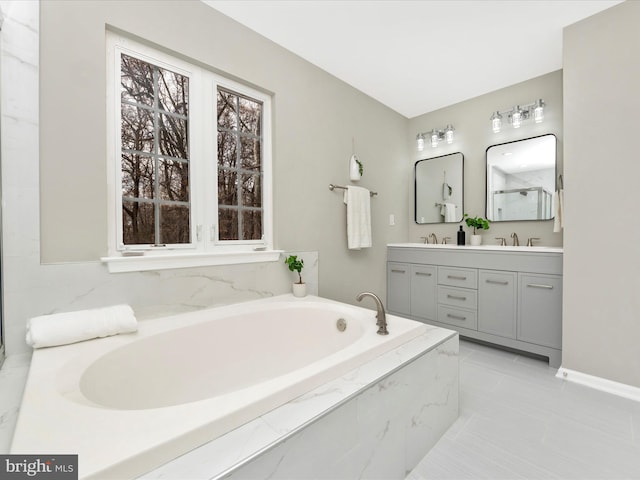 bathroom with tile patterned flooring, vanity, and a relaxing tiled tub