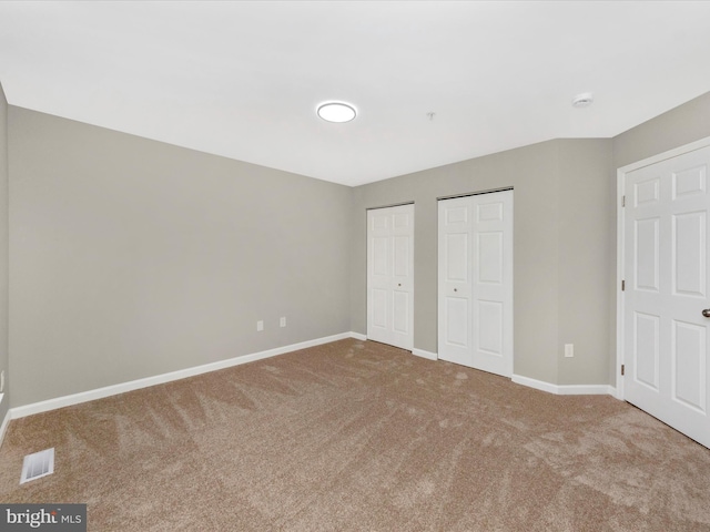 unfurnished bedroom with carpet flooring and multiple closets