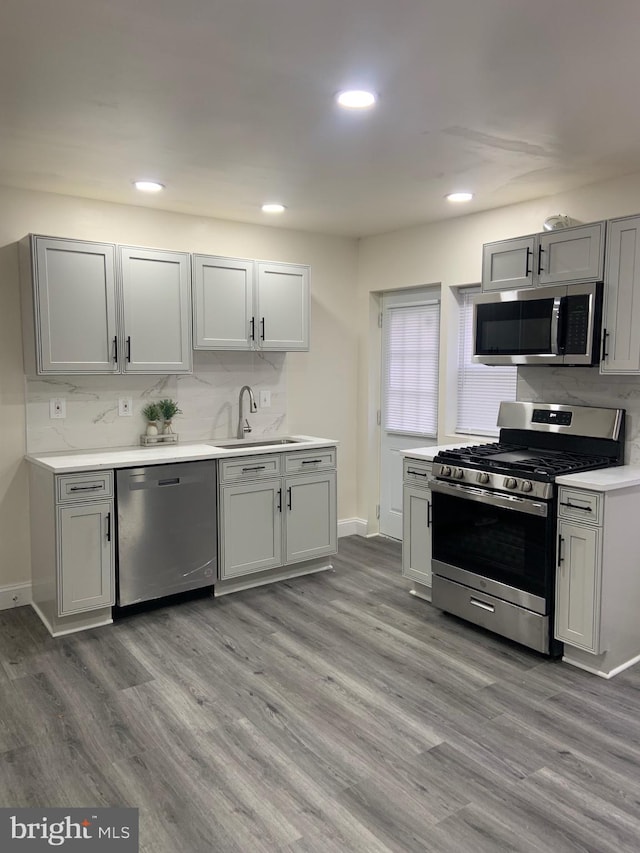 kitchen featuring light wood-type flooring, stainless steel appliances, gray cabinetry, and sink