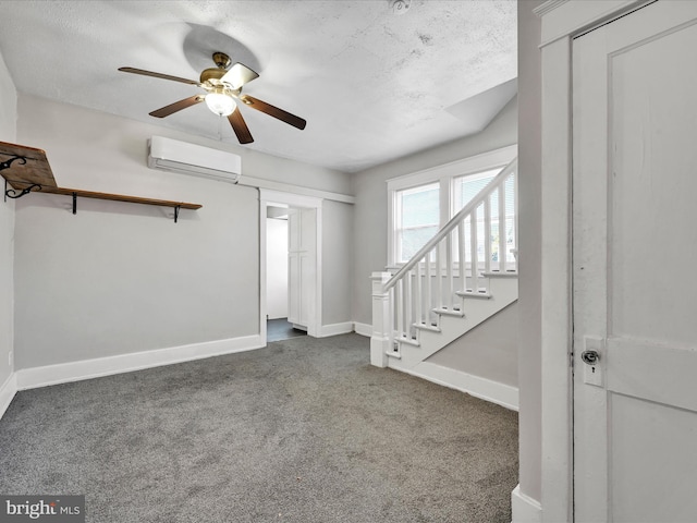 unfurnished living room with a wall mounted AC, ceiling fan, a textured ceiling, and dark colored carpet