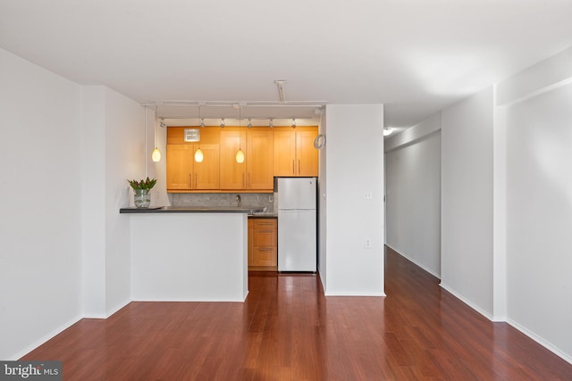 kitchen featuring baseboards, decorative backsplash, dark wood-type flooring, and freestanding refrigerator