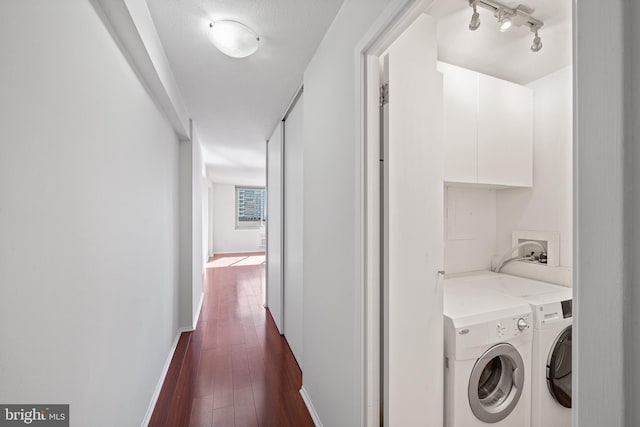 clothes washing area featuring cabinet space, baseboards, dark wood finished floors, washing machine and clothes dryer, and rail lighting