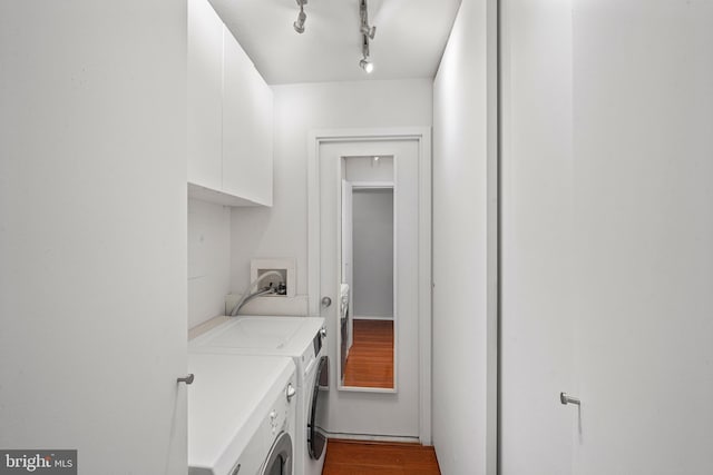 laundry room featuring dark wood-style floors, washer and clothes dryer, cabinet space, and track lighting