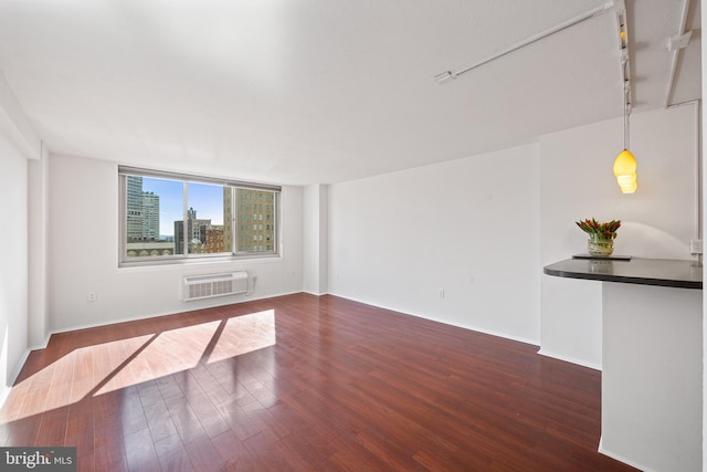 spare room with an AC wall unit, wood finished floors, and rail lighting