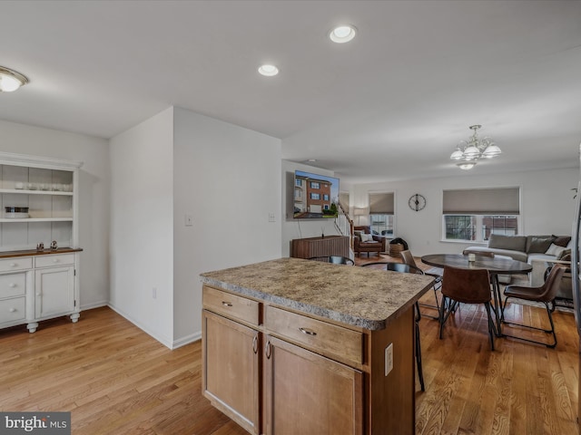 kitchen with an inviting chandelier, light hardwood / wood-style flooring, a kitchen island, and hanging light fixtures