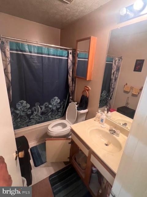 full bathroom with vanity, shower / tub combo, a textured ceiling, and toilet