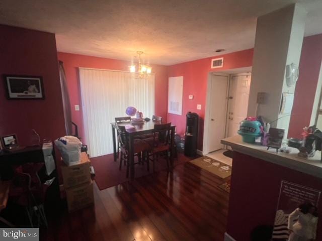 dining space with hardwood / wood-style floors and a notable chandelier