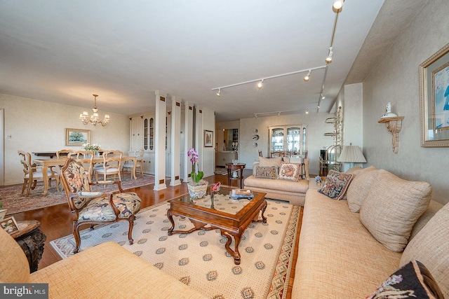 living area featuring wood finished floors, rail lighting, and an inviting chandelier