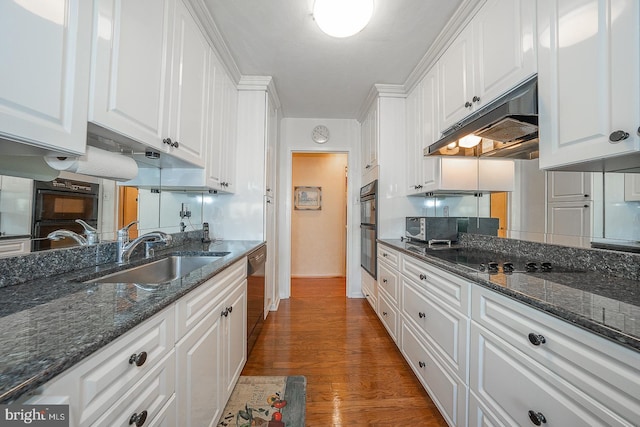 kitchen with black appliances, under cabinet range hood, white cabinets, and a sink