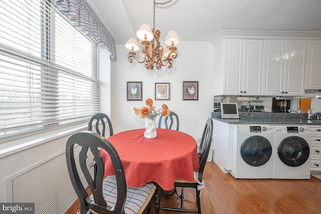 washroom with washer and clothes dryer, light wood-type flooring, a sink, and an inviting chandelier